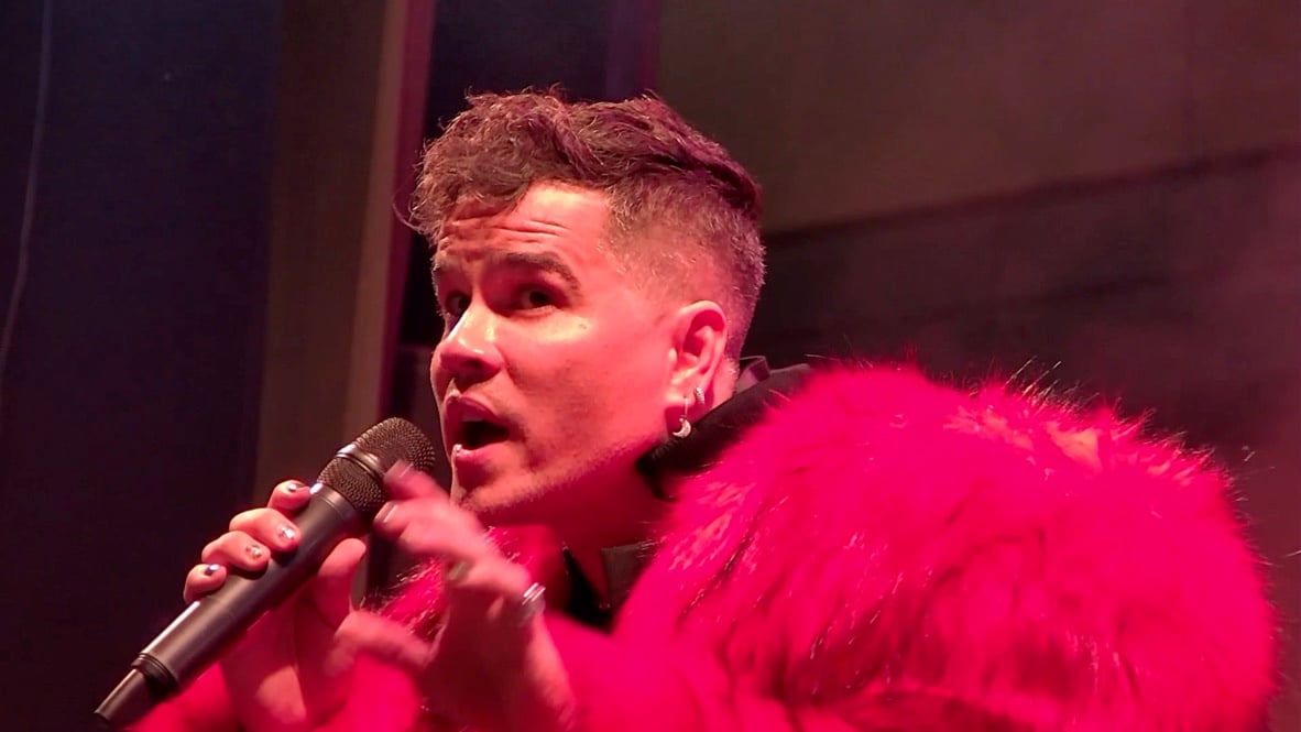 Primer plano de Lui da Motta cantando al micro con el pelo rojo.