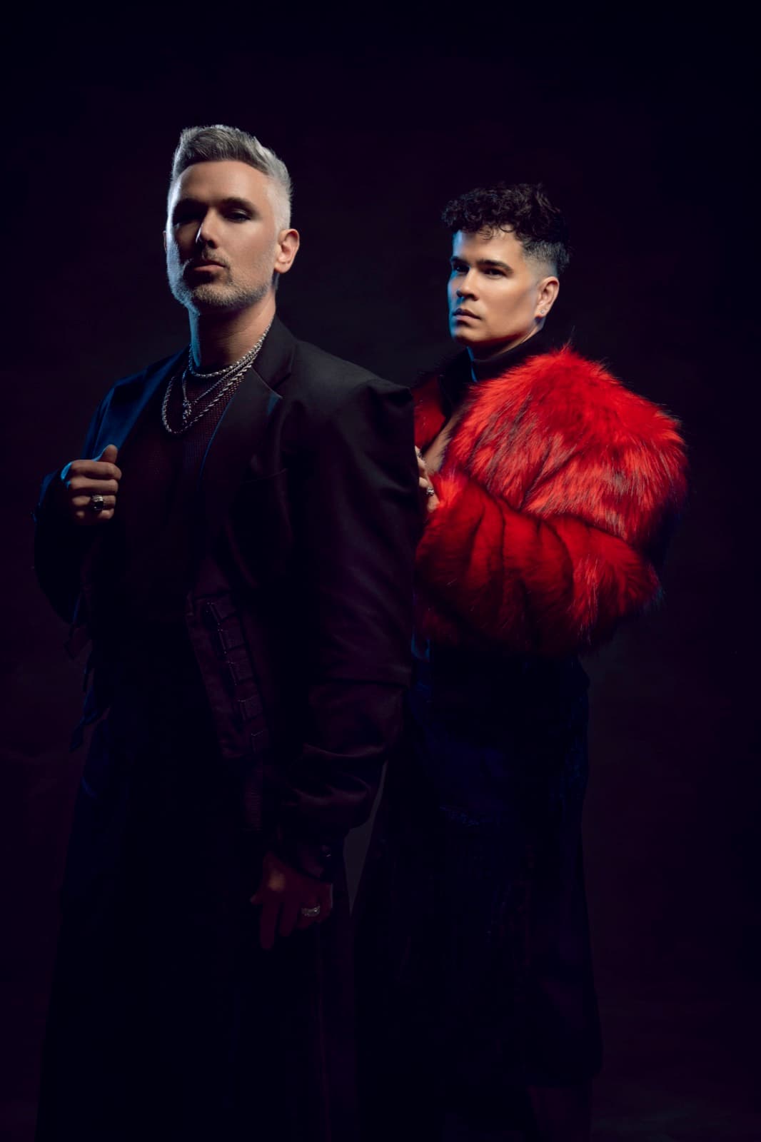 Velvet Riot — Eugin Vita en noir, Lui da Motta en fourrure rouge, studio sombre.