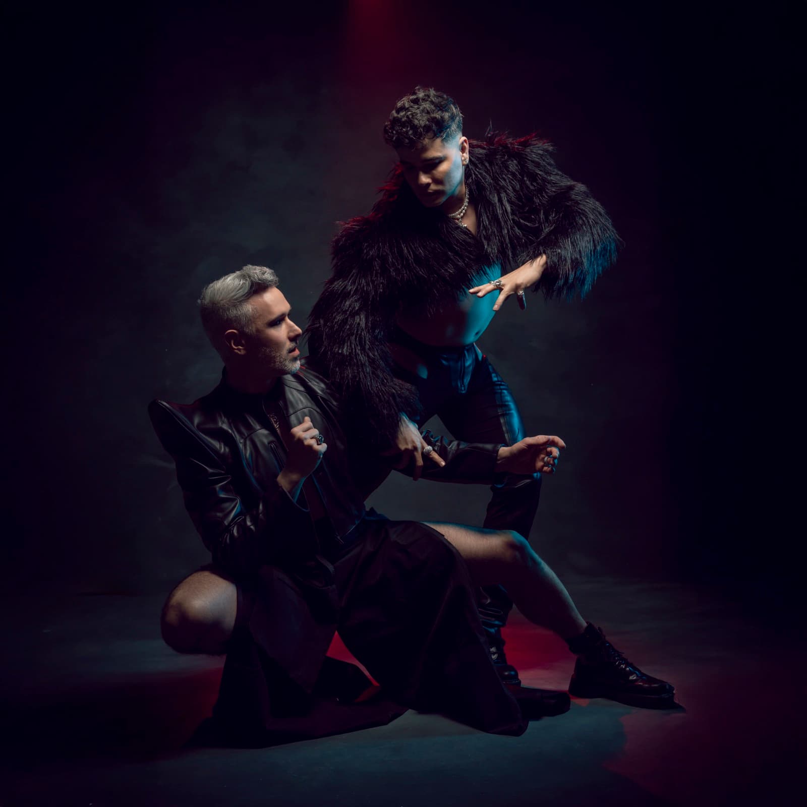 Velvet Riot — la pose de la pochette de SHAME, l'un assis, l'autre penché, lumière rouge et bleue.